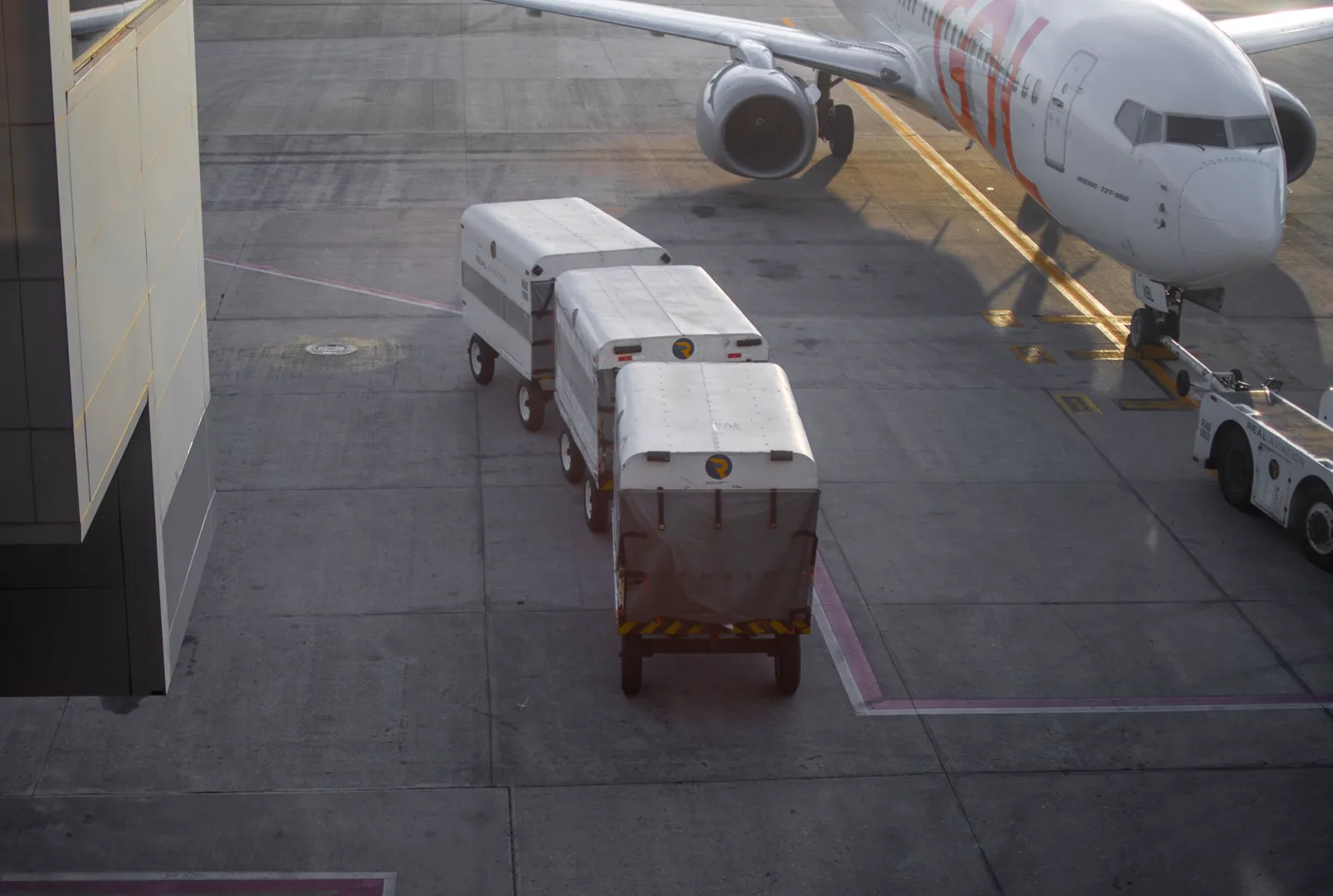 An aircraft at a gate with cargo units ready for loading