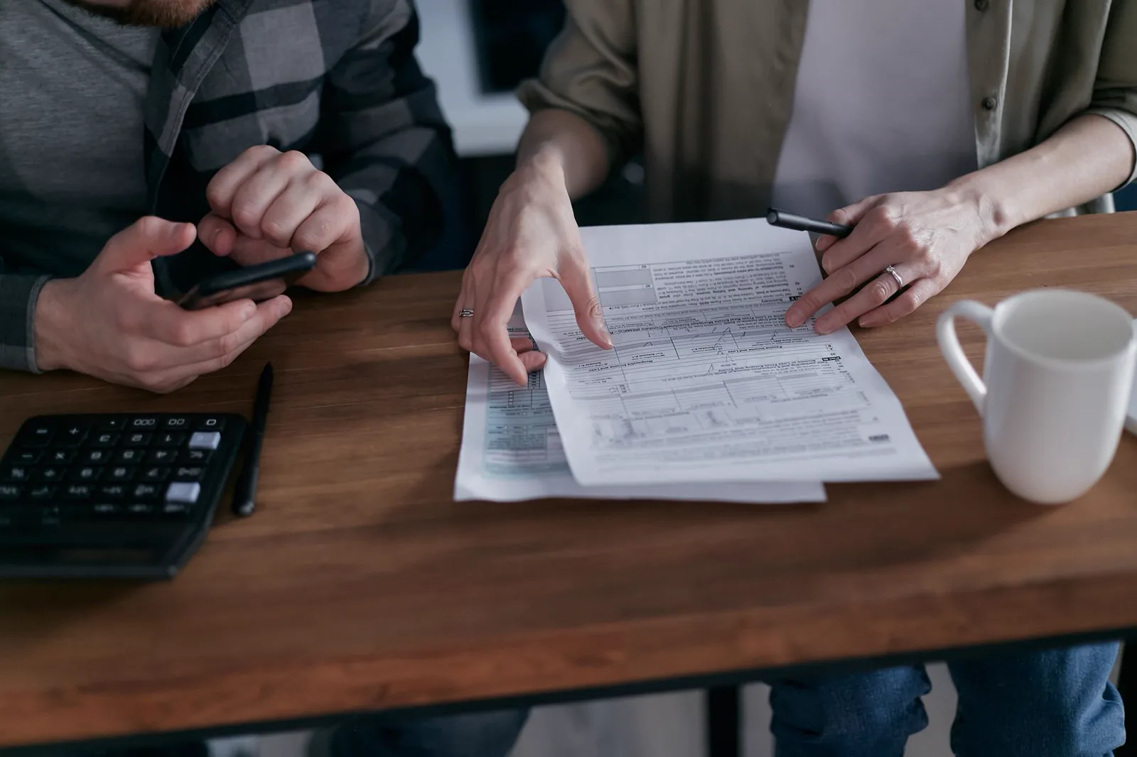Two people comparing financial documents with a calculator