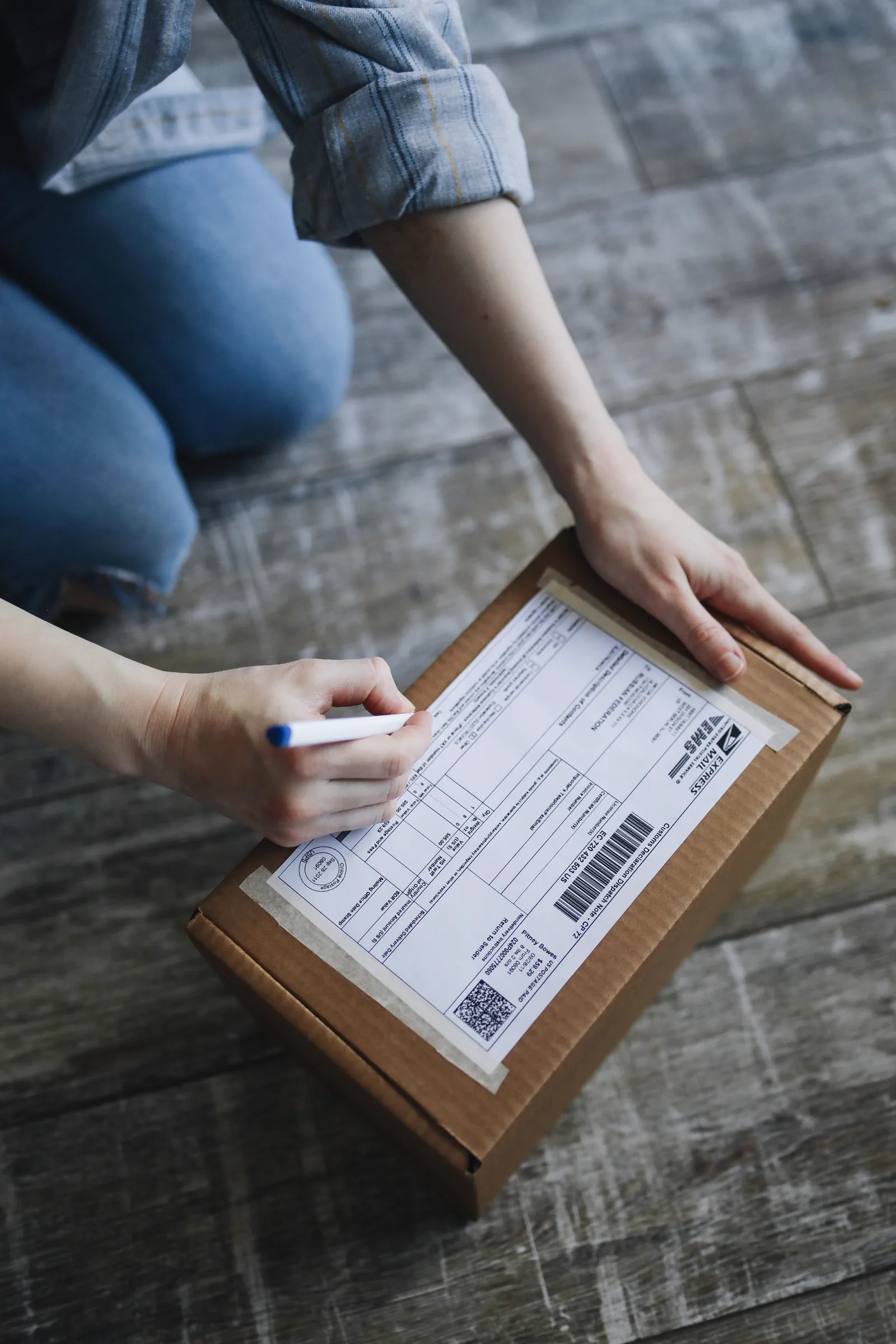 Hands writing shipment information on a cardboard package