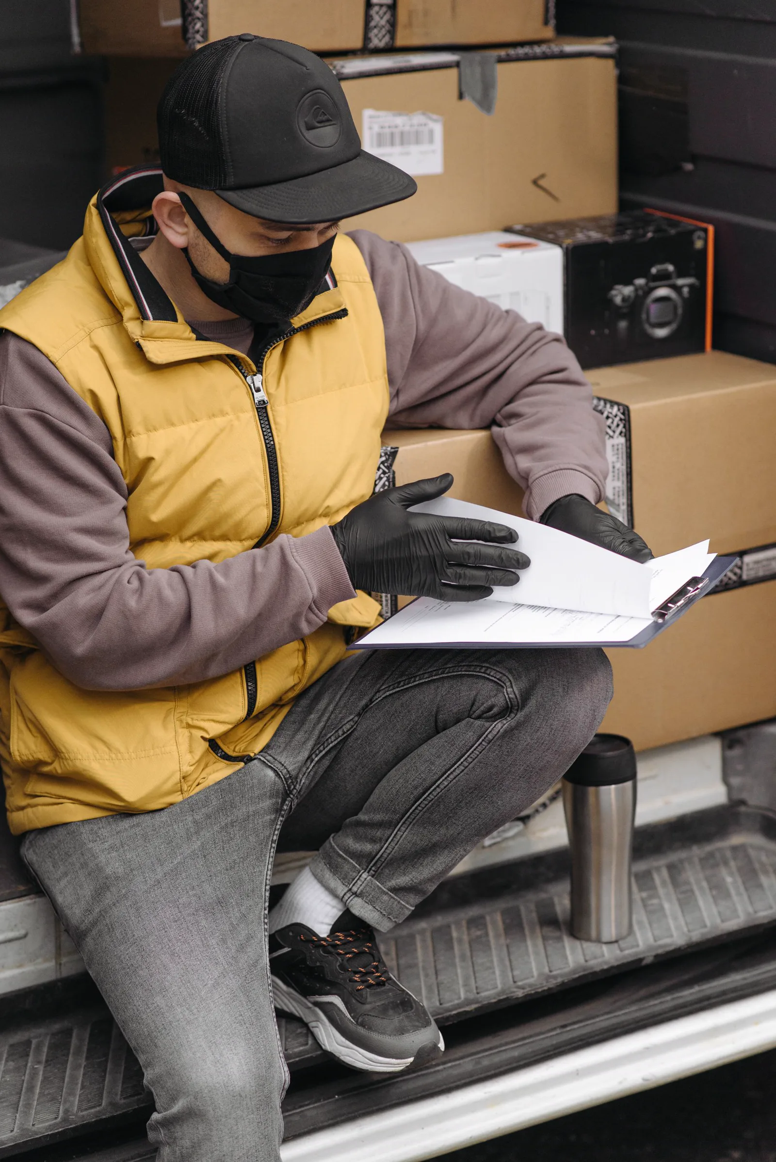 A delivery professional checking documents beside prepared packages